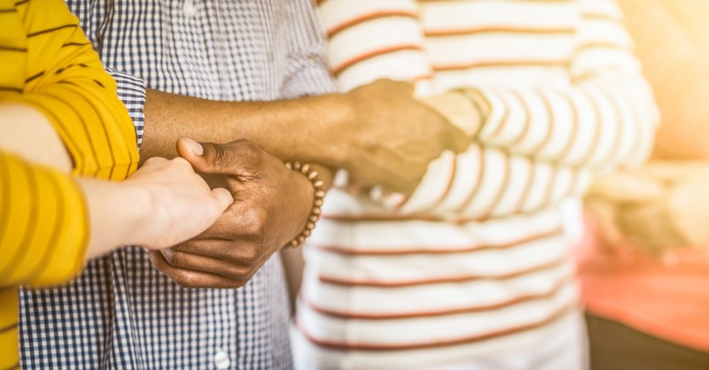 row of multicultural adults holding hands