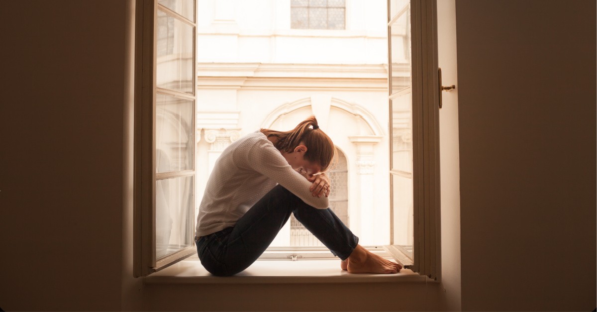 A stressed woman sitting on a window sill, Ed Young speaks on the virus of fear