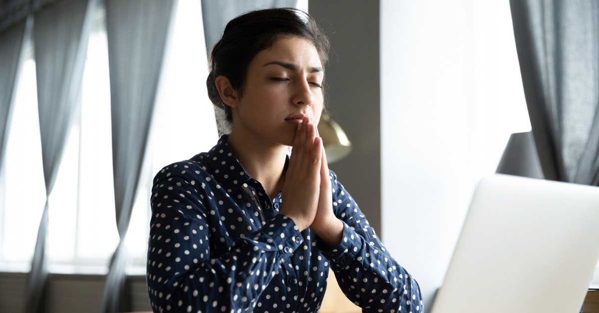 woman praying at laptop church at home COVID-19