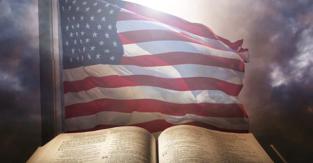 open Bible with US flag waving in background